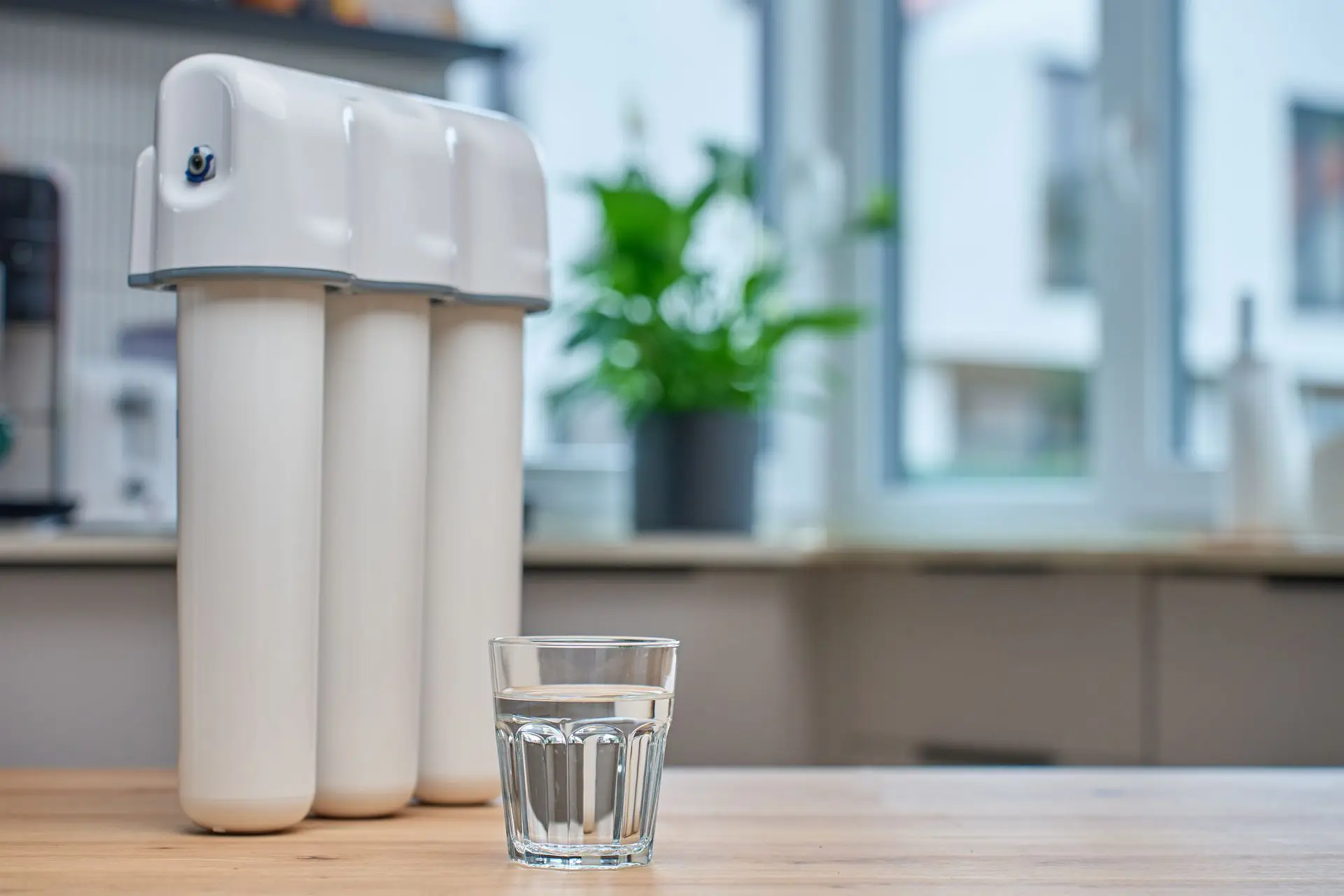 Countertop water filter beside a glass of clean water